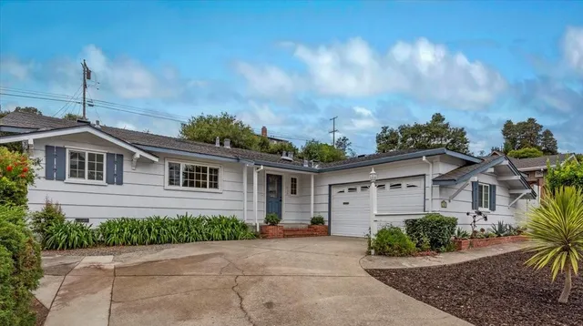 a front view of a house with a yard and potted plants