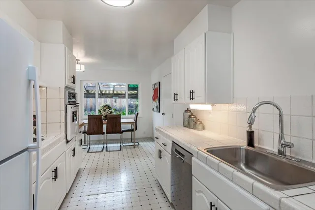 a kitchen with white cabinets a sink dishwasher and a stove with wooden floor