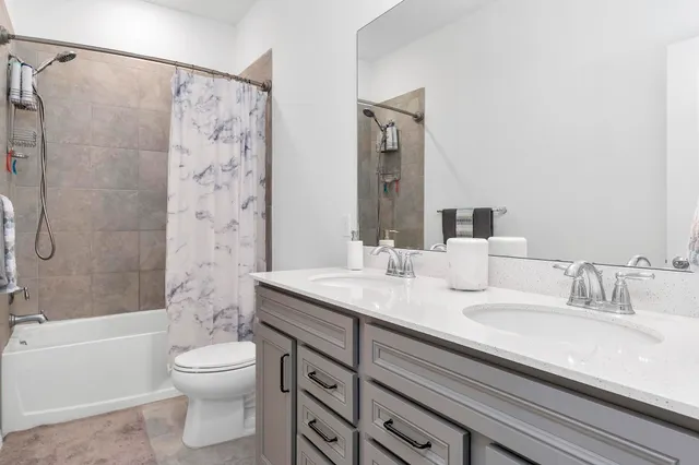 a bathroom with a granite countertop sink a toilet a mirror a bathtub and shower