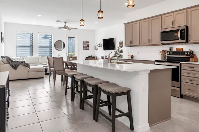 a kitchen with stainless steel appliances granite countertop a stove top oven a sink dishwasher a dining table and chairs with wooden floor