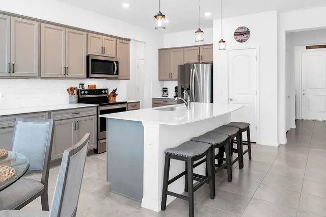 a kitchen with stainless steel appliances a table chairs microwave and refrigerator