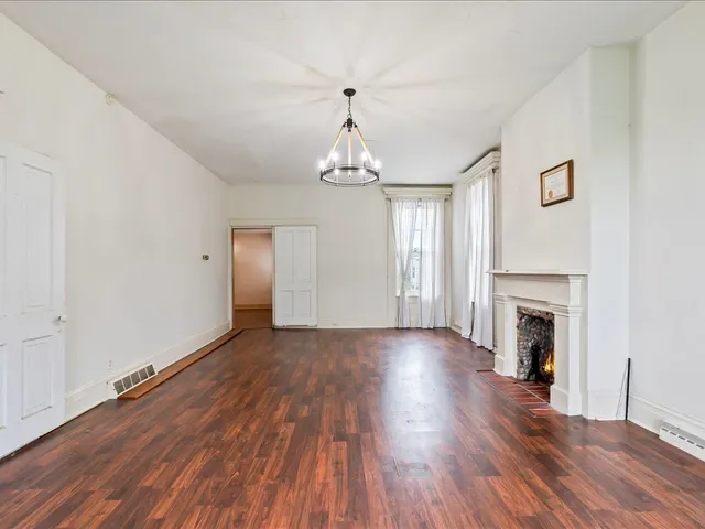 an empty room with wooden floor fireplace and windows
