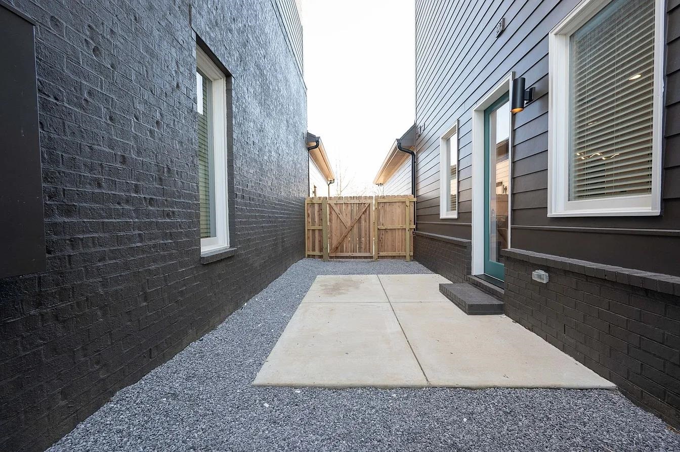 752 Meda Street Memphis, TN 38104 - Photo 17 of 18 Private side patio featuring concrete paving, gravel landscaping, and a wooden privacy fence with gate