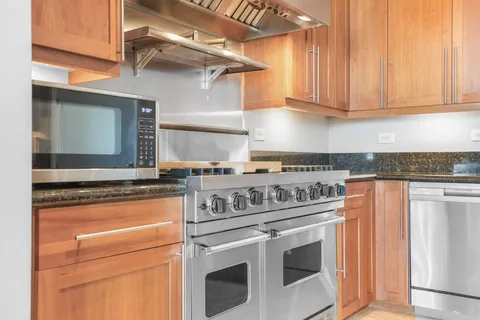 a kitchen with stainless steel appliances granite countertop a stove and white cabinets