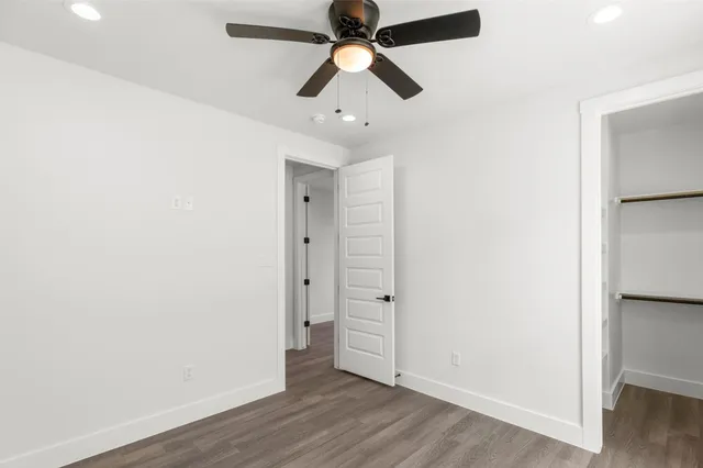 an empty room with wooden floor and a ceiling fan