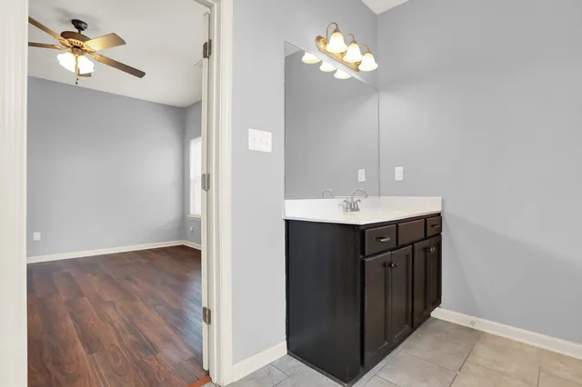 a view of an empty room with window a ceiling fan and wooden floor