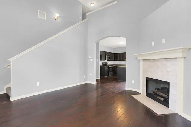 an empty room with wooden floor fireplace and windows
