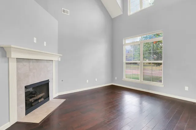 an empty room with wooden floor fireplace and windows