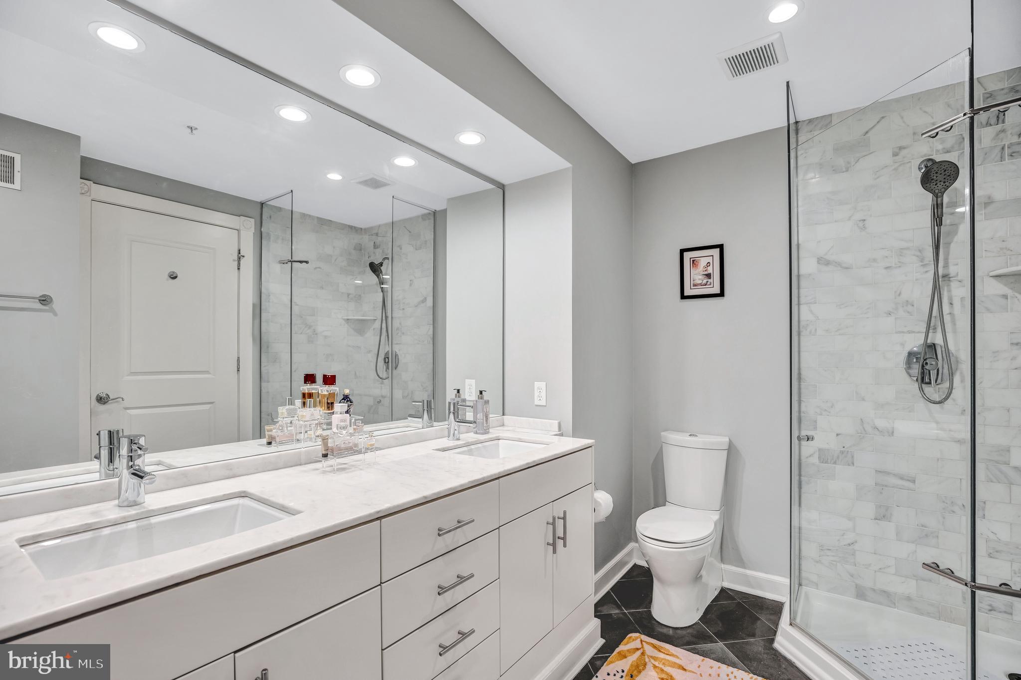 910 Powhatan Street, Unit 104N Alexandria, VA 22314 - Photo 21 of 60 a bathroom with a double vanity sink toilet mirror and shower