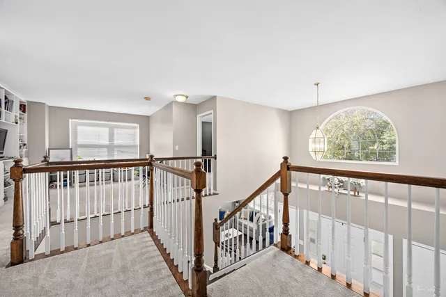 a view of staircase with lots of frames on wall and a large window