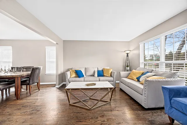 a living room with furniture floor to ceiling window and wooden floor