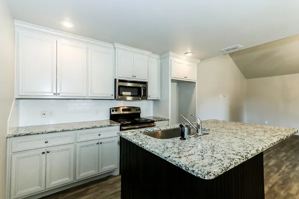 a kitchen with granite countertop white cabinets and a sink