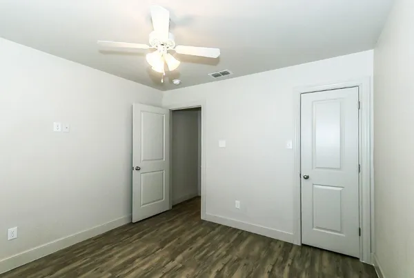 an empty room with wooden floor and fan