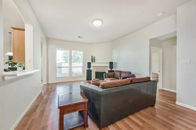 a view of a hallway with wooden floor and a bathroom