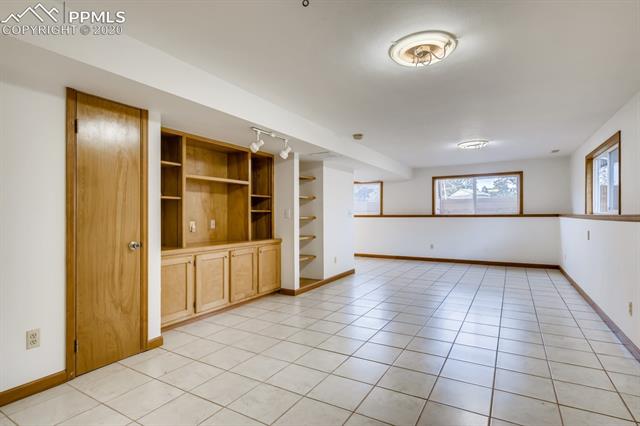 7575 Tobin Road Colorado Springs, CO 80908 - Photo 19 of 27 Lower level family room with built ins and storage. Nice tile floors and garden level windows