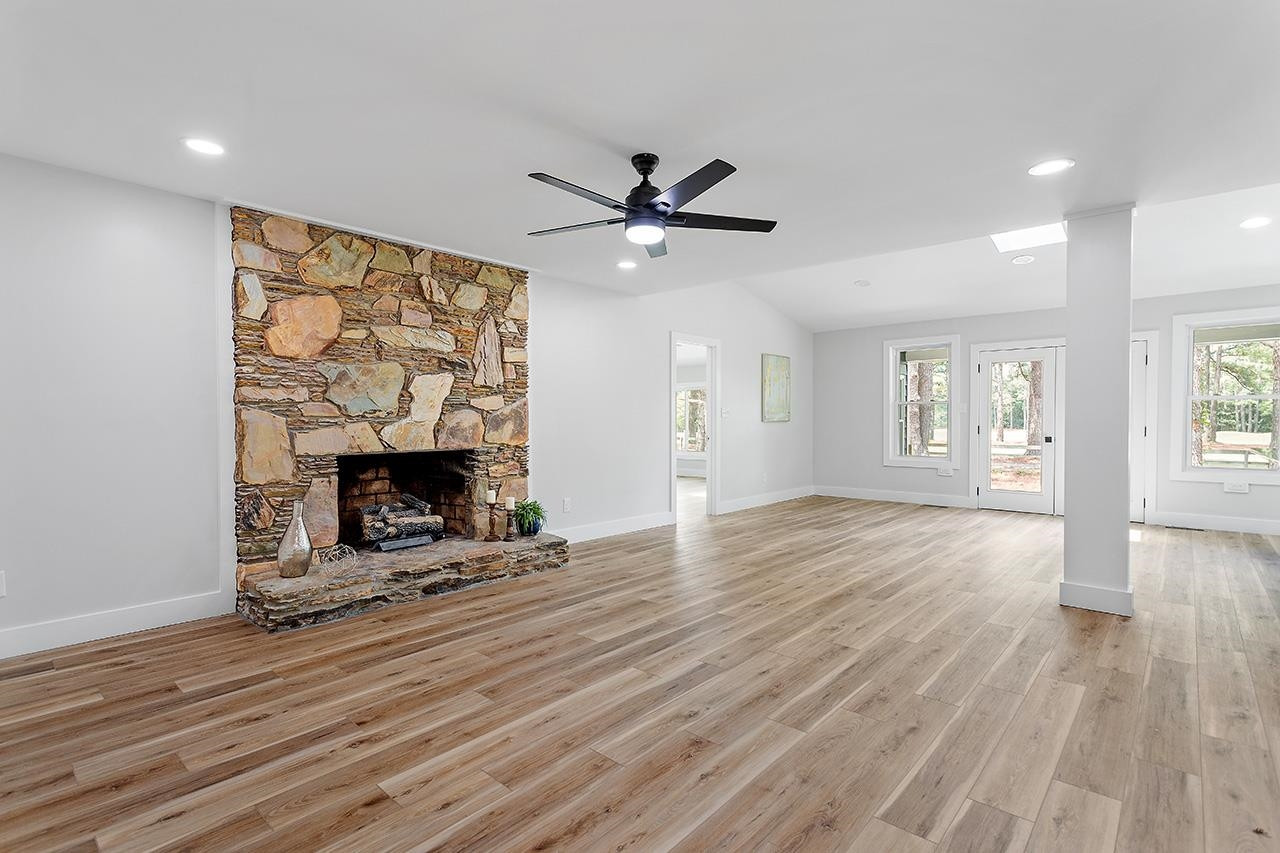 3420 East Garner Road Clayton, NC 27520 - Photo 10 of 30 a view of a livingroom with a fireplace a ceiling fan and wooden floor