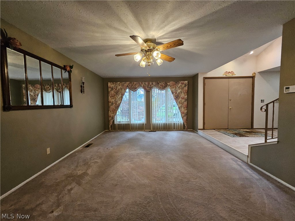 16551 Drake Road Strongsville, OH 44136 - Photo 26 of 50 Living Room featuring light carpet, a textured ceiling, large front windows, and ceiling fan