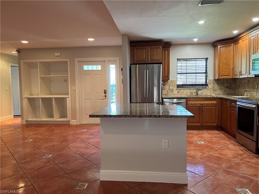 4724 32nd Avenue Southwest Naples, FL 34116 - Photo 18 of 39 a kitchen with stainless steel appliances granite countertop a stove a sink and a refrigerator