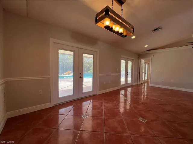 a view of an empty room with a chandelier fan and a window