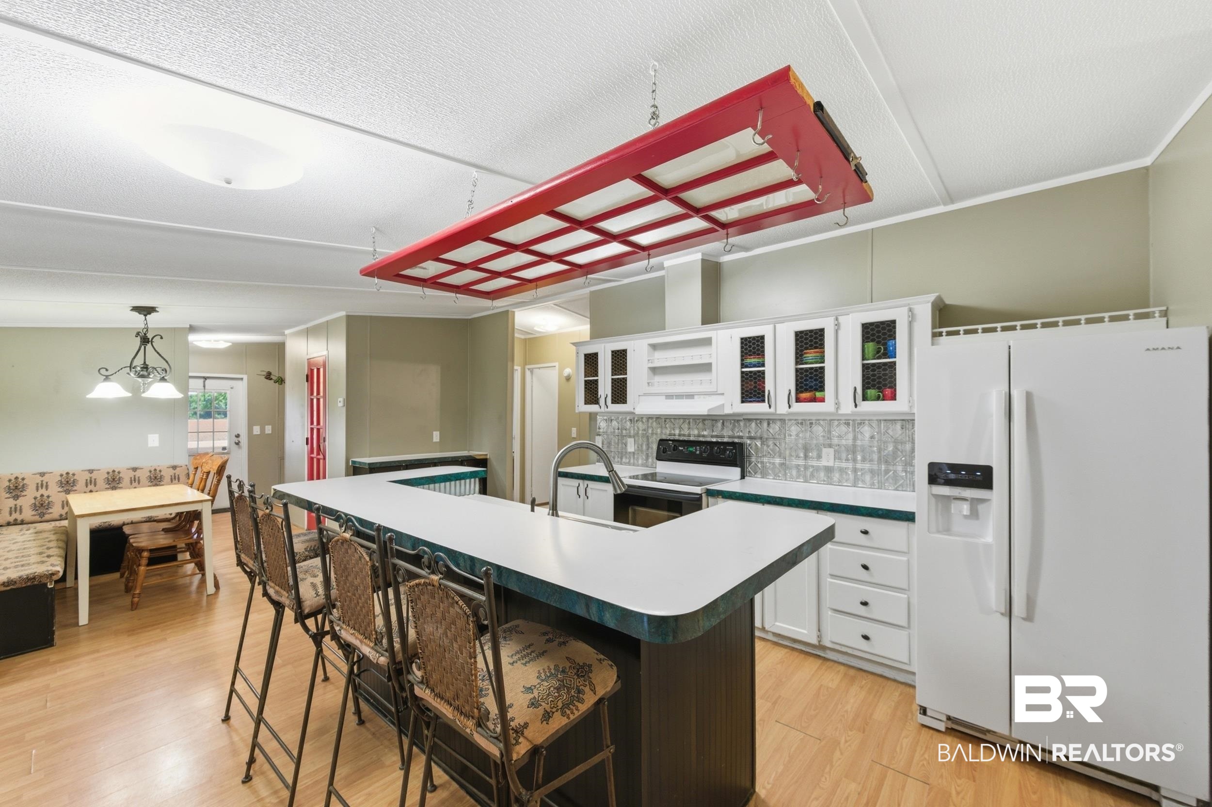 926 Tumbling Lane Atmore, AL 36502 - Photo 11 of 56 Kitchen featuring a U-shaped island with a sink, white cabinetry with glass-front uppers, a subway tile backsplash, and wood-finish flooring