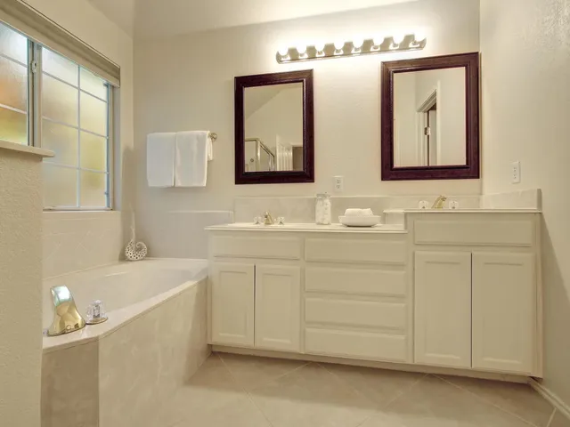 a bathroom with a double vanity sink mirror and bathtub