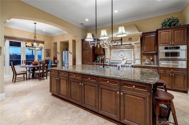 a kitchen with kitchen island granite countertop wooden cabinets and a chandelier