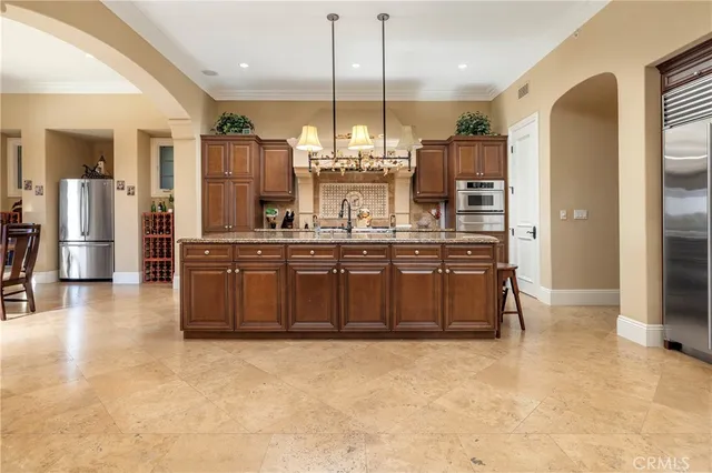 a kitchen with kitchen island granite countertop a stove a sink a refrigerator and a wooden cabinets