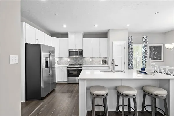 a kitchen with stainless steel appliances a sink a stove a refrigerator cabinets and a center island