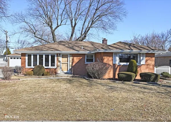 a front view of a house with a garden and trees