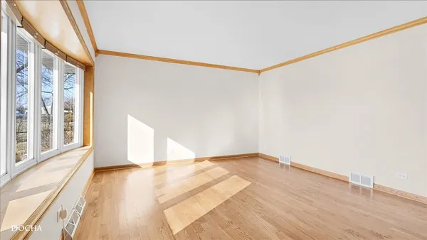 a view of an empty room with a window and hardwood floor