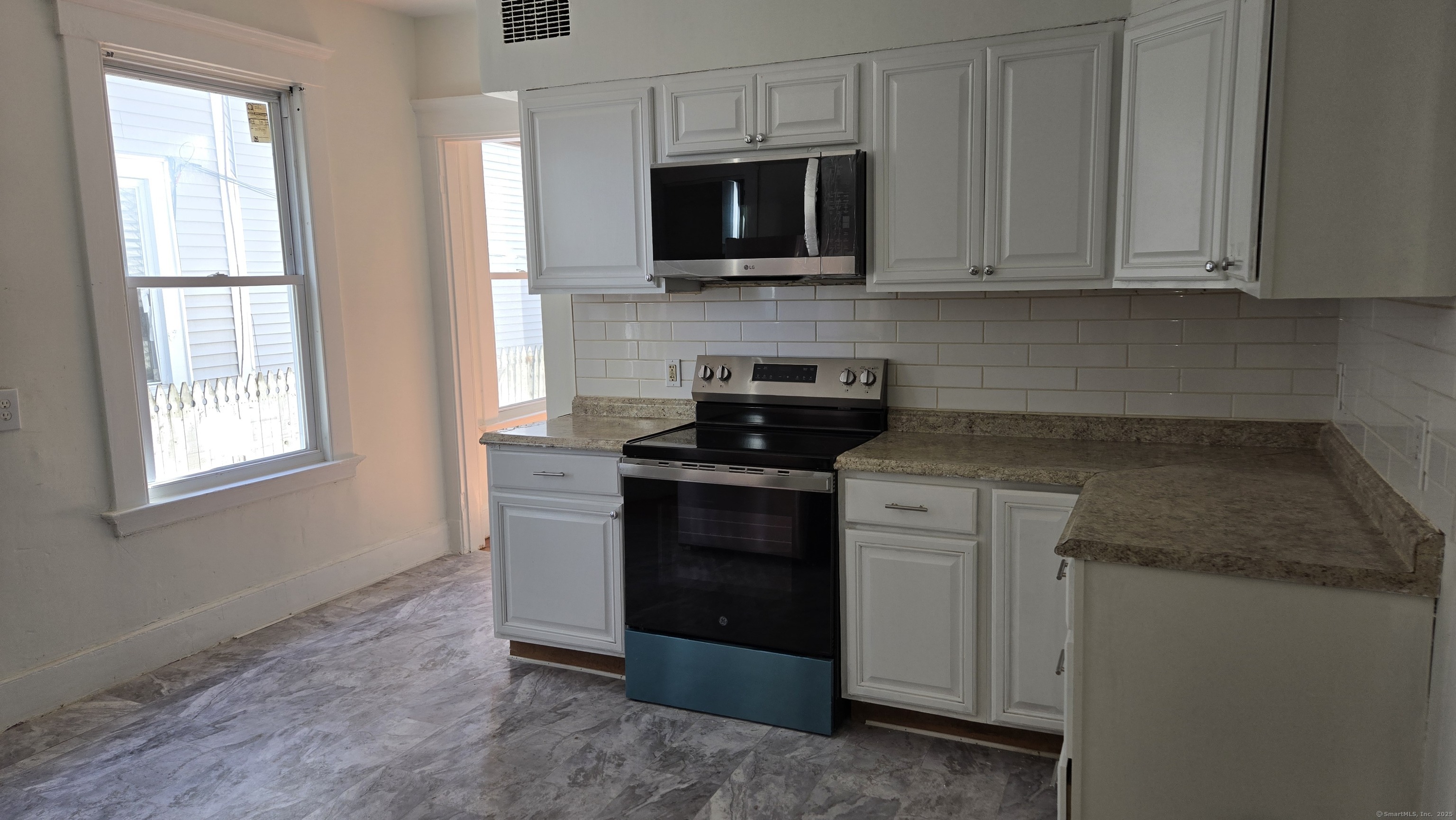 a kitchen with stainless steel appliances granite countertop white cabinets granite counter tops and a window