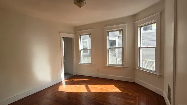 a view of an empty room with wooden floor and a window