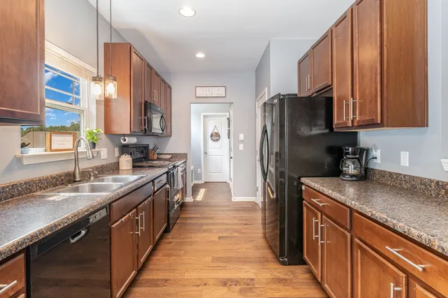 a kitchen with stainless steel appliances granite countertop a refrigerator a sink dishwasher a stove with wooden cabinets and a granite counter top