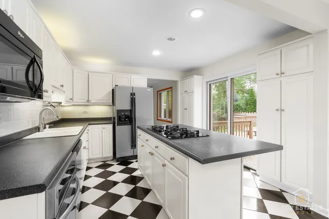 a kitchen with stainless steel appliances a sink a stove a refrigerator and cabinets