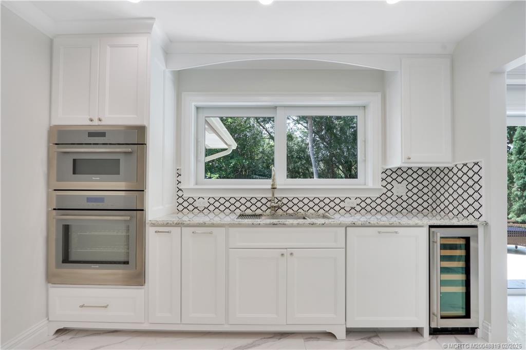 24 Emarita Way Sewall's Point, FL 34996 - Photo 15 of 26 a kitchen with white cabinets and a stove