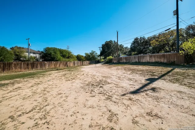 an empty room with a chandelier fan and windows