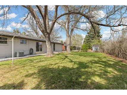 a backyard of a house with large trees and table and chairs
