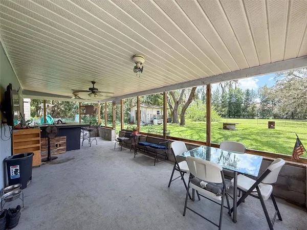 a view of a patio with table and chairs under an umbrella with a big yard