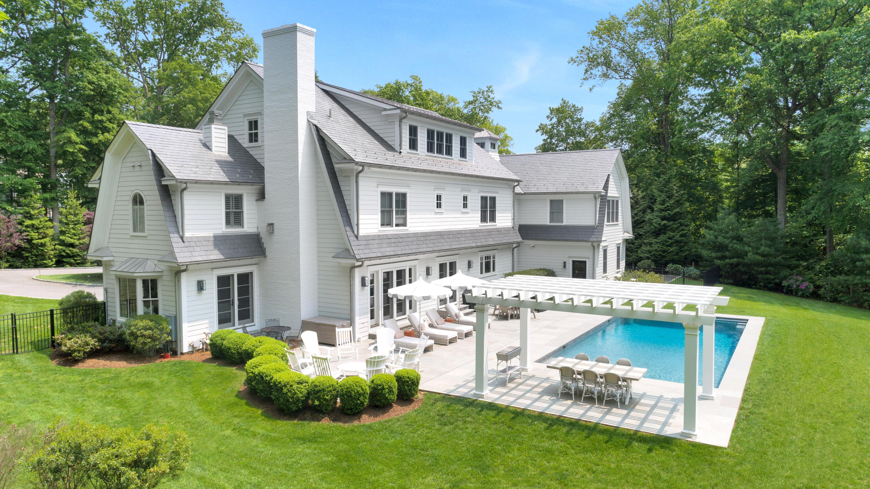 75 Parish Road New Canaan, CT 06840 - Photo 31 of 38 a front view of a house with a garden and swimming pool