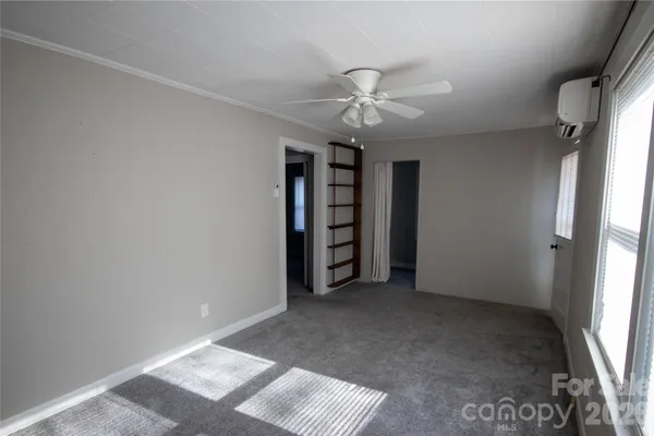 an empty room with a ceiling fan and window