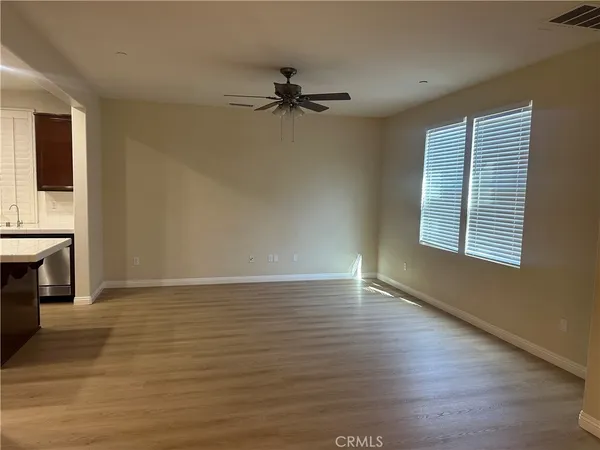 an empty room with wooden floor fireplace and windows