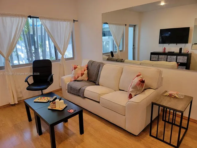 a living room with furniture a flat screen tv and a window