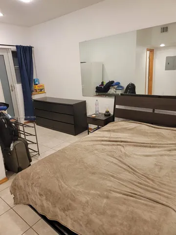 a bedroom with a bed and a flat tv screen on dresser