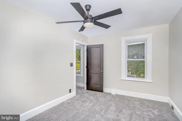 an empty room with a window and a fan