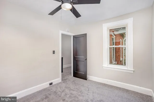 an empty room with a window and a fan