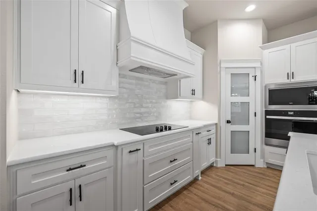 a kitchen with white cabinets and stainless steel appliances