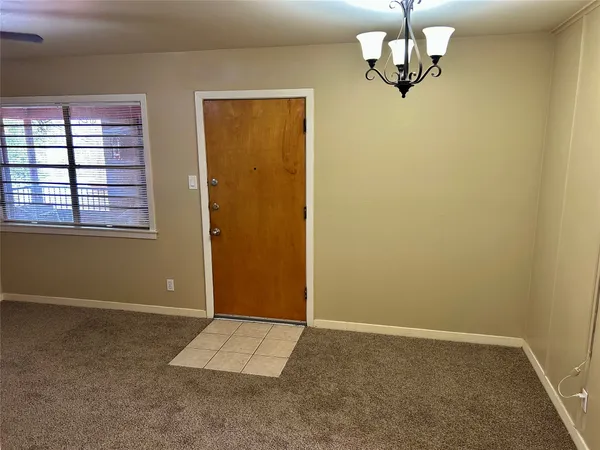 an empty room with chandelier fan and windows