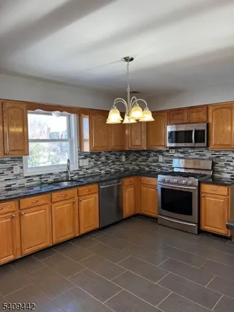 a large kitchen with stainless steel appliances granite countertop a stove and a sink