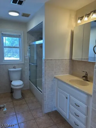 a spacious bathroom with a granite countertop sink a toilet and mirror