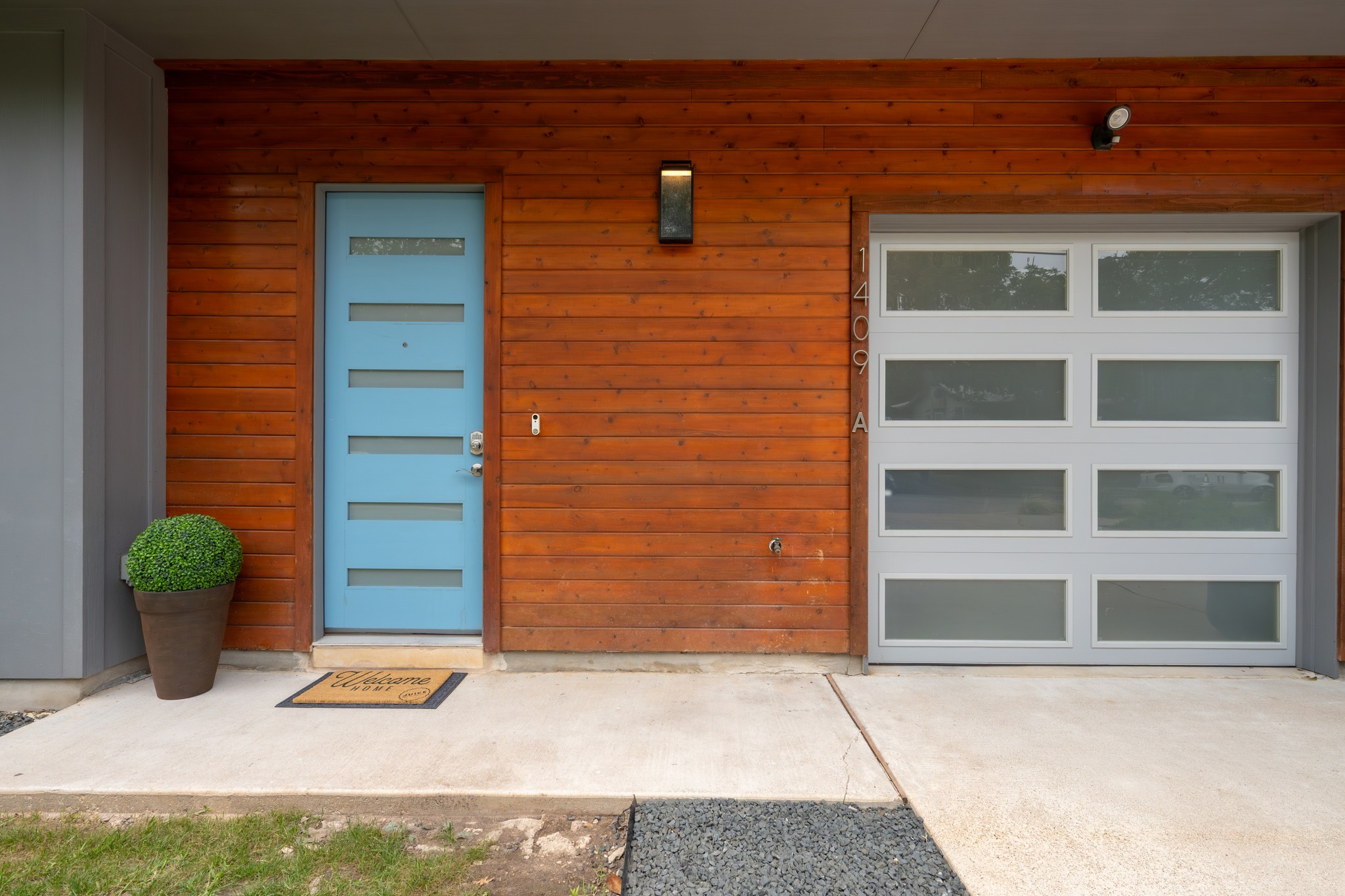 1409 Alegria Road, Unit A Austin, TX 78757 - Photo 3 of 24 Modern facade showcasing a vibrant blue entry door and sleek garage with window accents.
